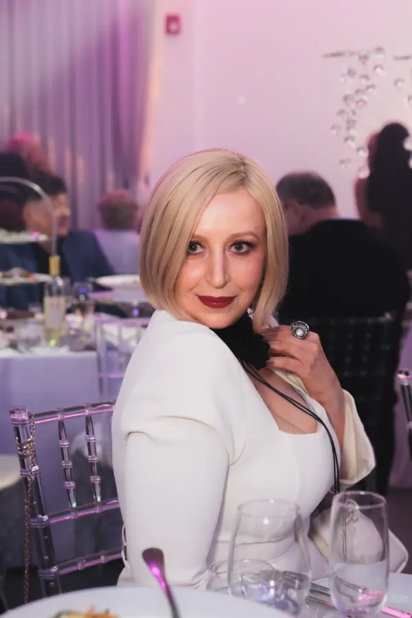 Blonde woman white blazer seated portrait