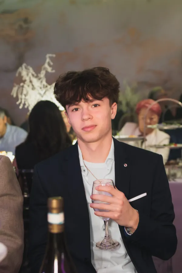 Teenage boy suit holding drink seated