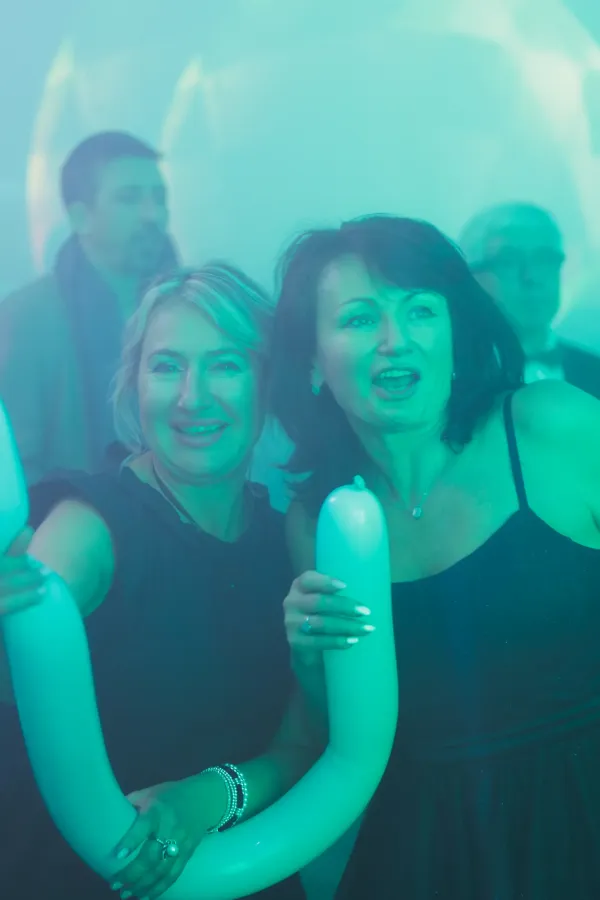 Two women dancing green light long balloon