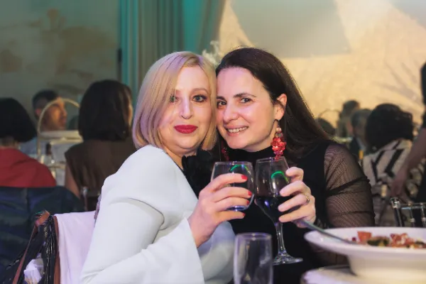 Two women toasting red wine seated