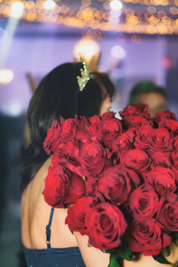 Woman tiara holding large red rose bouquet