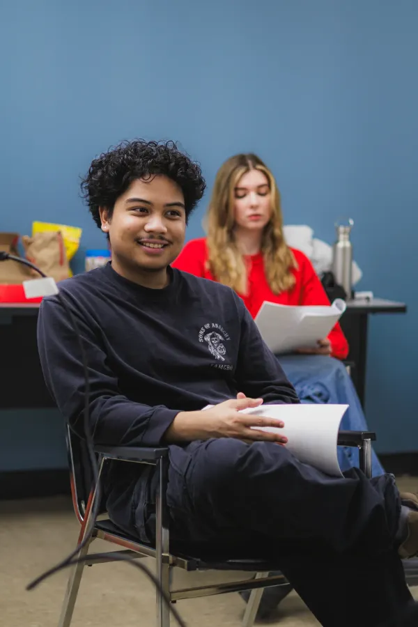 Bts director smiling script in hand blue wall