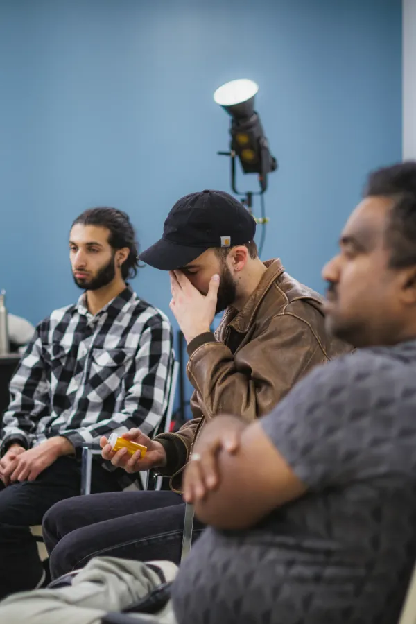 Bts three cast members seated watching blue wall