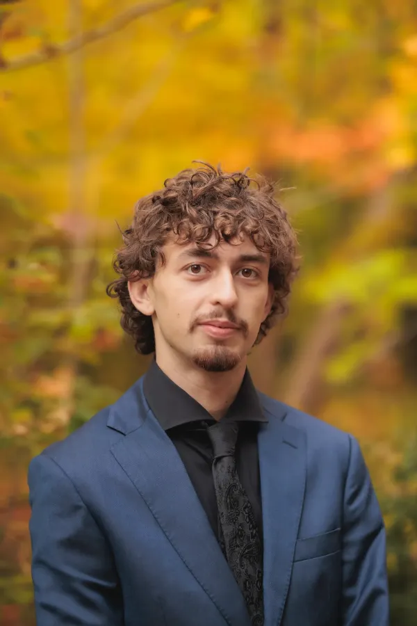Grad guy blue suit headshot autumn foliage
