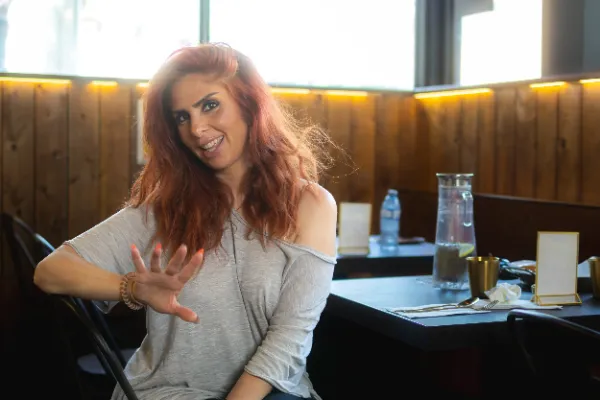 Female actor red hair grey top talking gesturing restaurant daytime