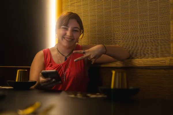 Female actor red top smiling holding phone restaurant booth