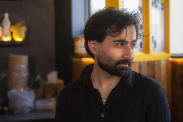 Male crew dark hair beard black shirt profile restaurant warmlight