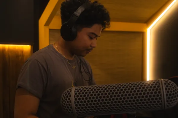 Sound recordist curly hair headphones handling boom mic studio warmlight
