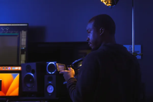 Crew member checking camera monitor recording studio blue light