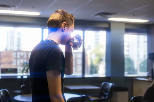 Crew member drinking coffee cup office hallway daytime