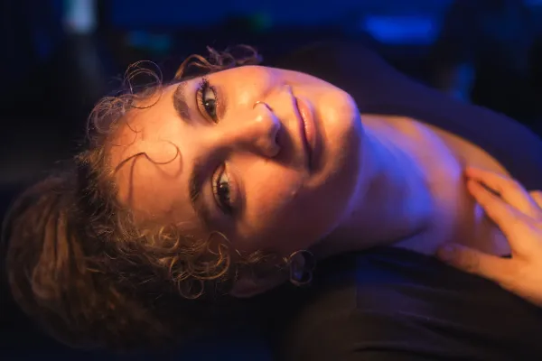 Female actor curly hair lying back warm blue light closeup
