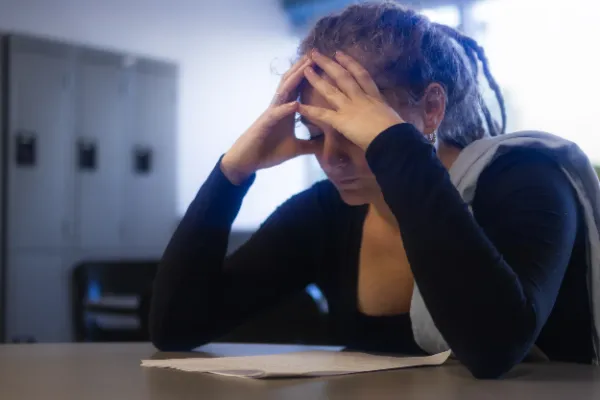 Female actor dreadlocks head in hands distressed classroom scene