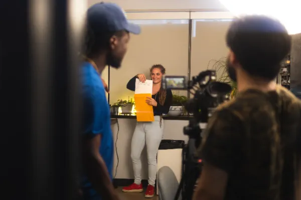 Female actor smiling holding manila envelope office set being filmed