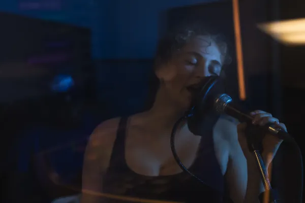 Female vocalist curly hair singing microphone blue orange light