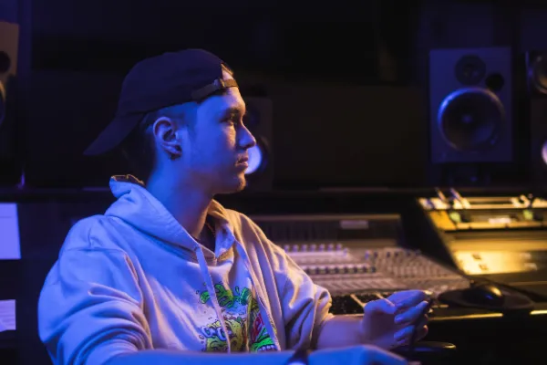 Producer white hoodie cap seated at mixing console blue light