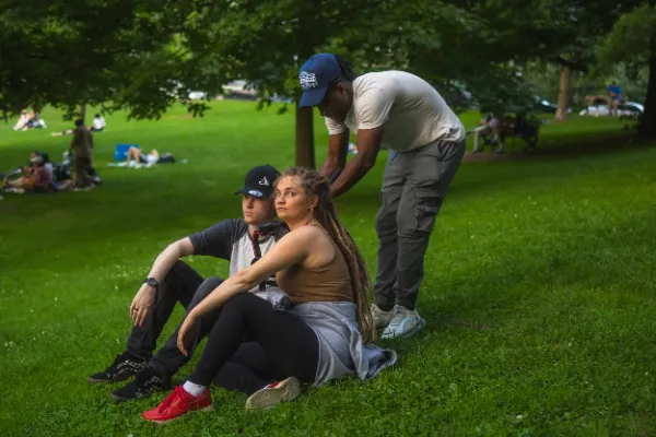 Director adjusting female actor hair two actors sitting park grass