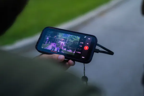 Director reviewing live camera feed on phone park path dusk