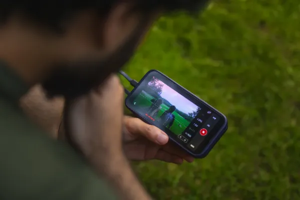 Director reviewing live feed on phone monitor park outdoor