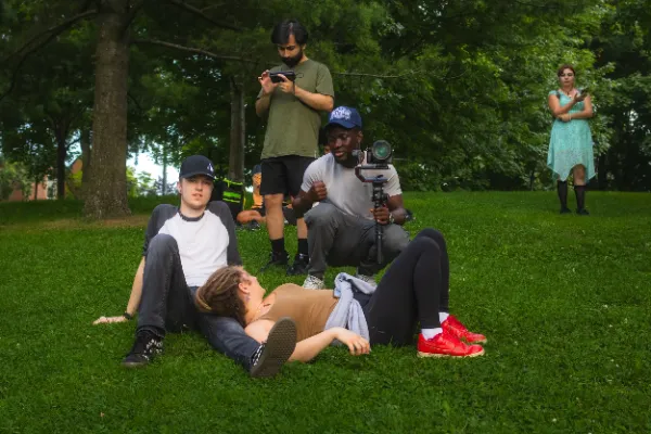 Full crew filming park lawn scene actors on grass wide shot
