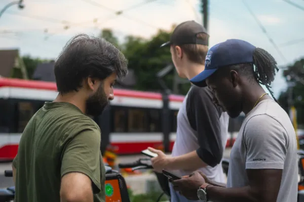 Three crew members reviewing phones toronto streetcar background