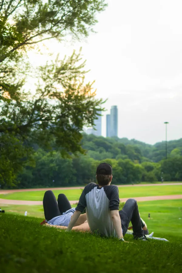 Two actors resting on park hillside city skyline overcast golden hour