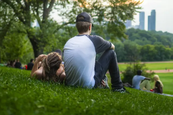 Two actors sitting on park hillside city skyline background