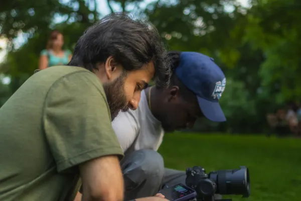 Two crew members huddled reviewing camera monitor park outdoor