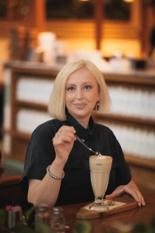 LF blonde bob black dress stirring latte cafe smiling portrait 09
